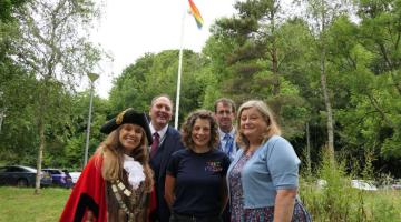 Staff and councillors from West Devon Council photographed under a pride rainbow flag flying outside the offices at Kilworthy Park.
