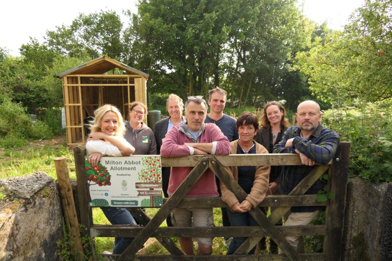 The Milton Abbot allotment group leaned against the gate of the new allotment site with Councillors Ursula Mann and Neil Jory.