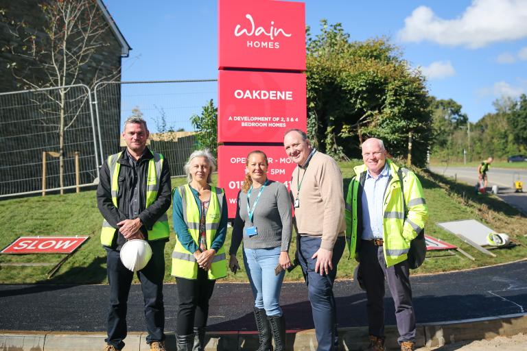 5 people standing in front of entrance to housing development