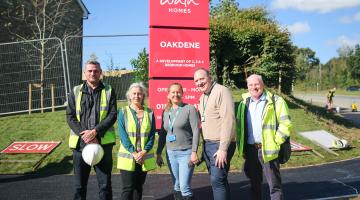 5 people standing in front of entrance to housing development